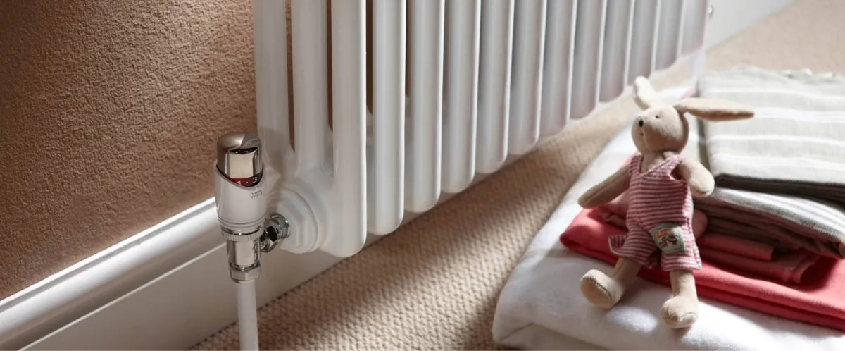 the bottom of a radiator, showing the valve and a stuffed toy