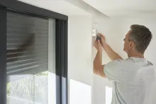A man installs the Wiser Shades Control Micro Module for Smart control of electric blinds