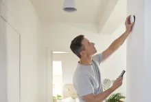 A man fits the Wiser Motion Sensor to the wall