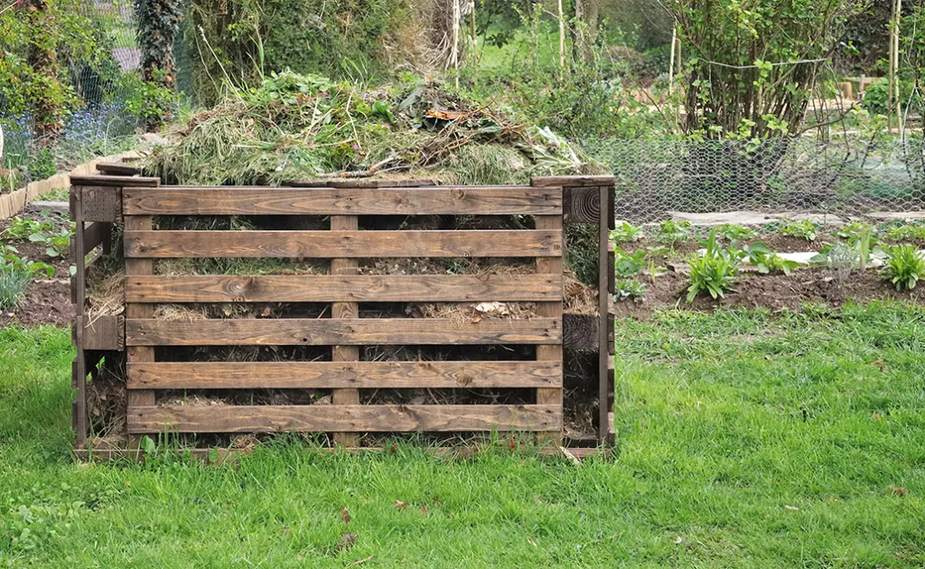 A photo of a large wooden compost bin in a garden