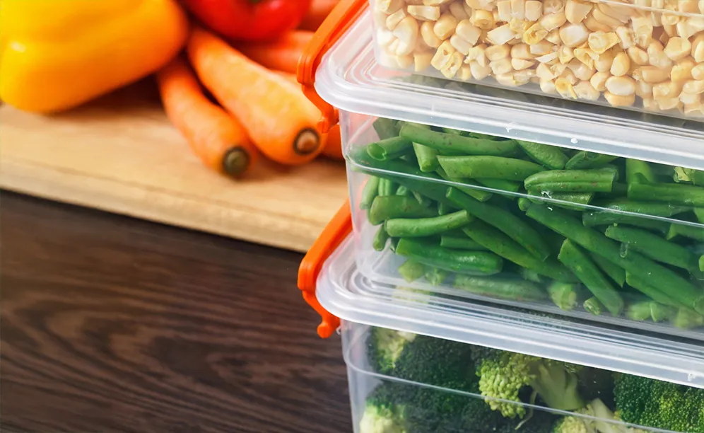 A photo of food stored inside storage containers near a chopping board